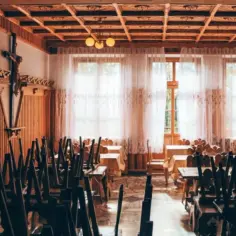 Drewniane wnętrze z krzyżem i stołami nakrytymi obrusami. Widać tu ślady dawnej świetności, być może miejsca związanego z zakonem jezuitów.