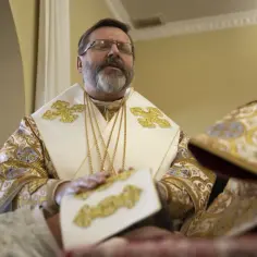 Biskup grekokatolik inaczej, w bogato zdobionej szacie, z zamkniętymi oczami, podczas nabożeństwa.