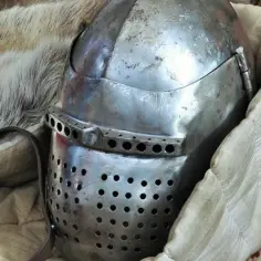Zbroja templariuszy w Polsce. Metalowy hełm z otworami, otoczony futrem i tkaniną, sugeruje historyczne artefakty.