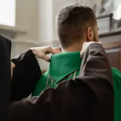 Siostra zakonna pomaga księdzu założyć zieloną szatę liturgiczną. To piękny widok, jak pielęgnują swój duchowy habit.