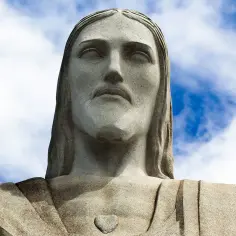 Kamienna twarz Jezusa w Rio, wznosząca się ku błękitnemu niebu z chmurami.