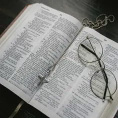 Modlitwa do świętej Moniki. Krzyż na otwartej Biblii, symbol wiary i nadziei.