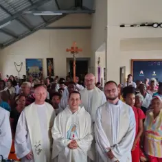 Niech będzie pochwalony Jezus Chrystus. Grupa wiernych zgromadzona w kościele, z księżmi na pierwszym planie.