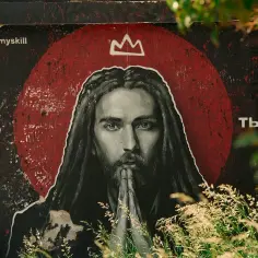 Mural z pytaniem "Kto ty?", przedstawiający postać z długimi włosami i koroną, skłania do refleksji: czy Jezus istniał?