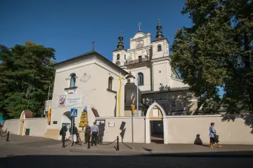 Kościół z wieżami i zegarem, obok tablica "Panie, przymnóż nam wiary". Miejsce pielgrzymek, być może związane z 12 objawieniami maryjnymi uznanymi przez kościół.