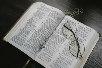 Modlitwa do świętej Moniki. Krzyż na otwartej Biblii, symbol wiary i nadziei.