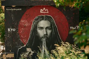 Mural z pytaniem "Kto ty?", przedstawiający postać z długimi włosami i koroną, skłania do refleksji: czy Jezus istniał?