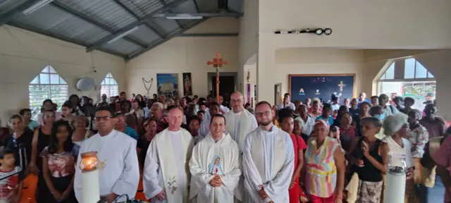 Niech będzie pochwalony Jezus Chrystus. Grupa wiernych zgromadzona w kościele, z księżmi na pierwszym planie.